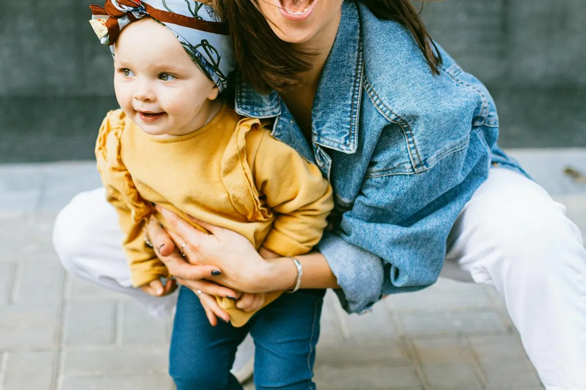 Mère accroupie qui rit en tenant son bébé contre elle
